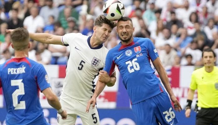 John Stones berduel udara dengan Ivan Schranz di laga Inggris vs Slovakia, Minggu (30/6/2024)